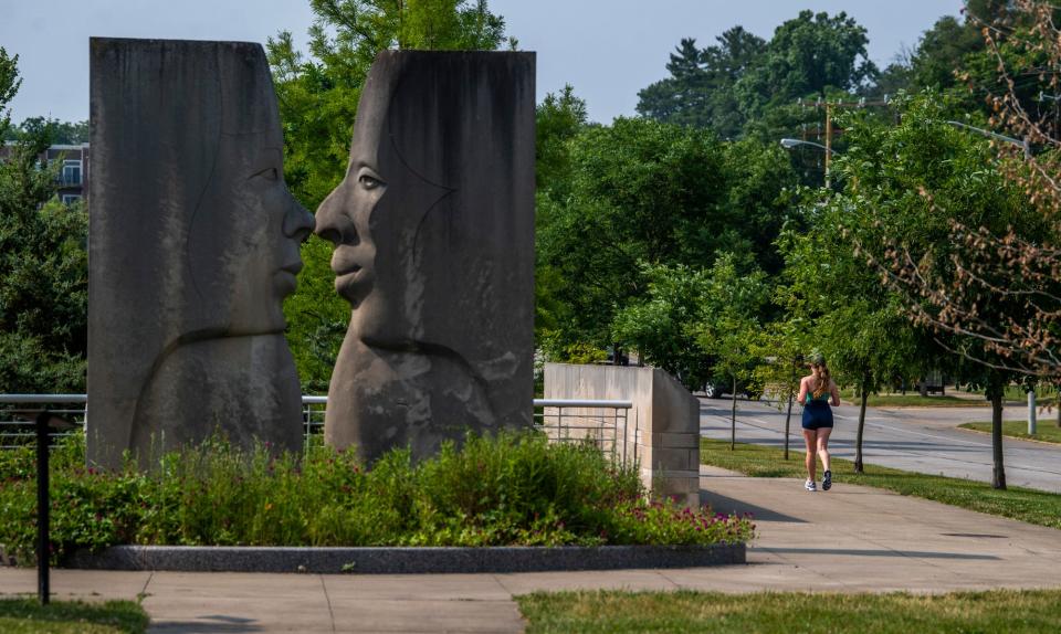 A jogger runs near the Jean-Paul Darriau limestone carving in Millers-Showers Park in June.
