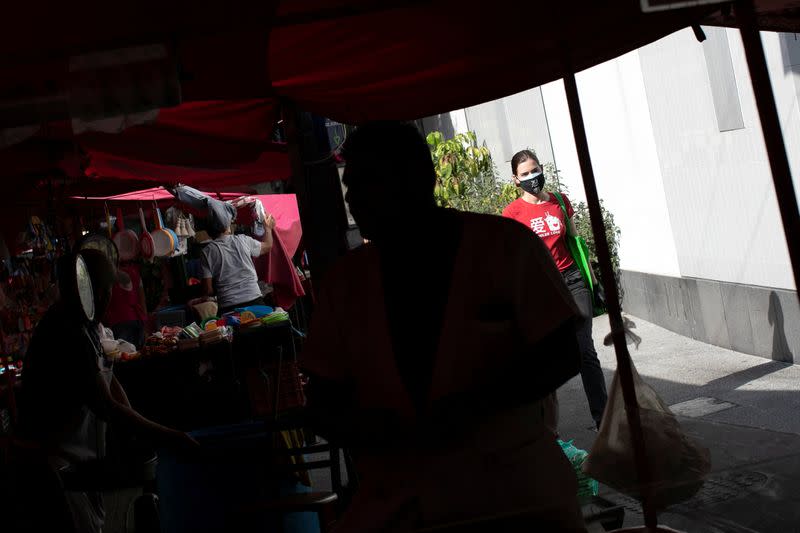 A woman walks past vendors at the local street market after Mexico's government declared a health emergency on Monday and issued stricter rules aimed at containing the fast-spreading coronavirus disease (COVID-19), in Mexico City