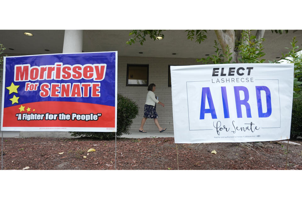 A voter walks past election signs at a polling precinct Tuesday, Jun. 20, 2023, in Surry, Va. Lashrecse Aird is running against Virginia State Sen. Joe Morrissey in a Democratic primary for a newly redrawn Senate district. (AP Photo/Steve Helber)