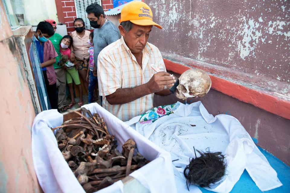 Don Venancio Tuz Chi, one of the administrators of the Pomuch cemetery, cleans the bones and skulls of a deceased relative of the Colli Ycauch family at the cemetery on Oct. 22, 2022. He has been a hired bone cleaner for more than 20 years, and he is paid $1.50 per skeleton.