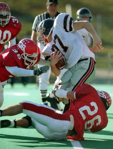 St. John's Peter Nyako, left, and teammate Terrence Gaffney take down Longmeadow's Jamison Humphries during the 2001 Central/Western Mass. Division 1 Super Bowl at Springfield College.