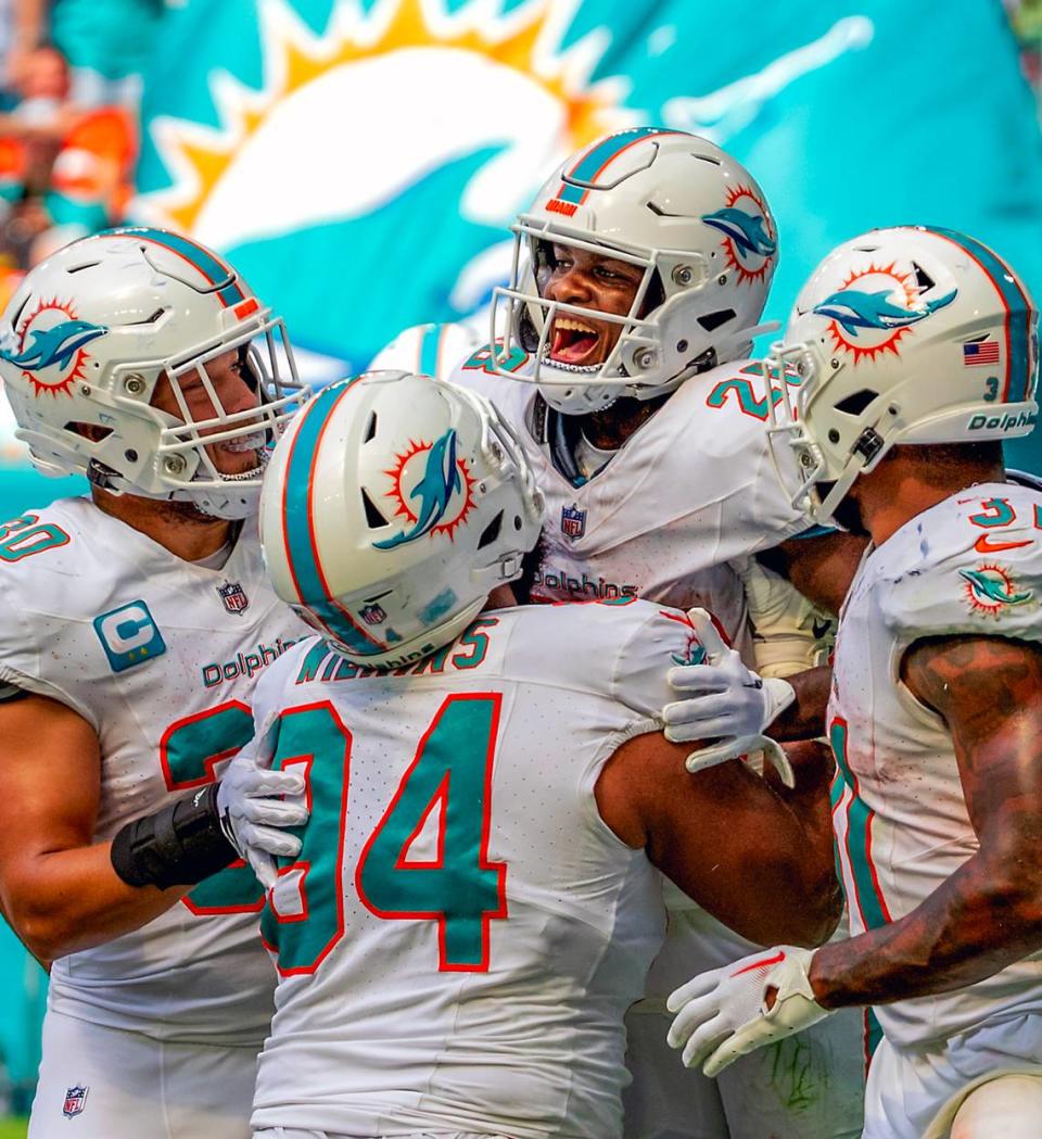 Miami Dolphins running back De’Von Achane (28) celebrates with teammates Alec Ingold (30) Christian Wilkins (94) and Raheem Mostert (31) after scoring a touchdown against the Denver Broncos during fourth quarter of an NFL football game at Hard Rock Stadium on Sunday, Sept. 24, 2023 in Miami Gardens, Fl.