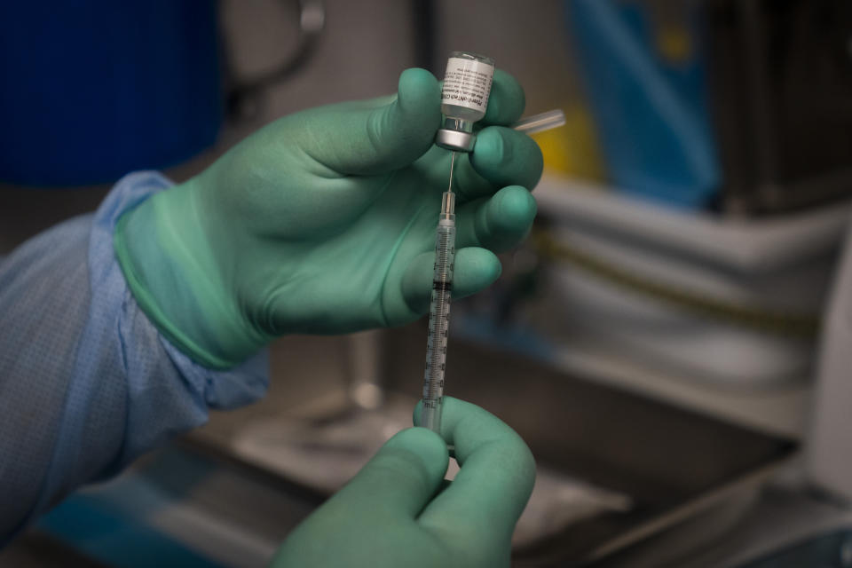 FILE - In this Aug. 26, 2021 file photo, Parsia Jahanbani prepares a syringe with the Pfizer COVID-19 vaccine in a mobile vaccine clinic operated by Families Together of Orange County in Santa Ana, Calif. An international group of scientists is arguing the average person doesn't need a COVID-19 booster yet — an opinion that highlights the intense scientific divide over the question. (AP Photo/Jae C. Hong, File)