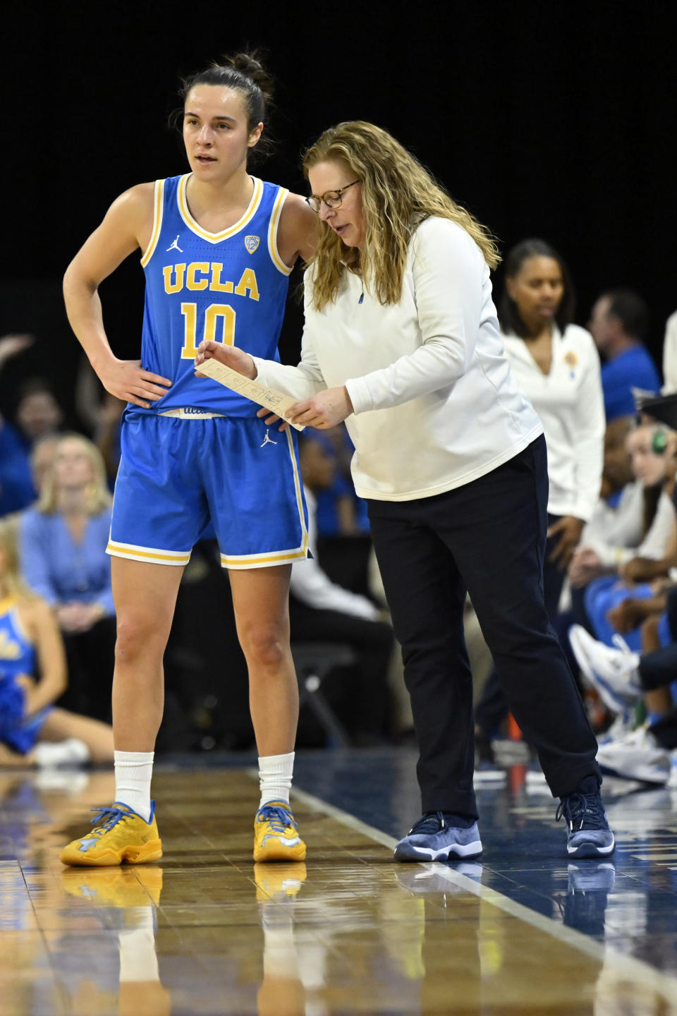 UCLA guard Gina Conti (10) and head coach Cori Close talk during a timeout during the first half of an NCAA college basketball game against Arizona in the quarterfinal round of the Pac-12 women's tournament Thursday, March 2, 2023, in Las Vegas. (AP Photo/David Becker)