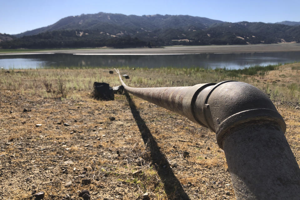 A pipe runs to Lake Mendocino near Ukiah, Calif., on Wednesday, Aug. 4, 2021. Tourists flock to the picturesque coastal town of Mendocino for its Victorian homes and cliff trails, but visitors this summer will also find public portable toilets and dozens of signs on picket fences announcing the quaint Northern California hamlet: "Severe Drought Please conserve water." The town of Mendocino gets some of their water from the reservoir, but most of the lake water goes to Sonoma County. (AP Photo/Haven Daley)