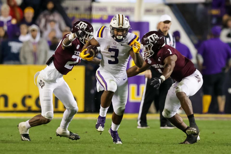 Nov 27, 2021; Baton Rouge, Louisiana, USA;  LSU Tigers running back Tyrion Davis-Price (3) runs between Texas A&M Aggies defensive back Antonio Johnson (27) and linebacker Aaron Hansford (1) during the first half at Tiger Stadium. Mandatory Credit: Stephen Lew-USA TODAY Sports