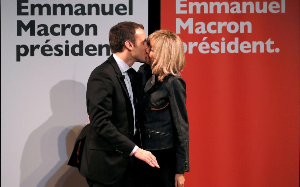Mr Macron kisses his wife Brigitte as they attend a meeting for Women's Day in Paris in March. - Credit: Reuters