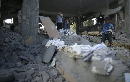 A Palestinian boy collects copies of the Koran from the remains of a mosque, which witnesses said was hit by an Israeli air strike, in Beit Hanoun in the northern Gaza Strip August 25, 2014. REUTERS/Mohammed Salem