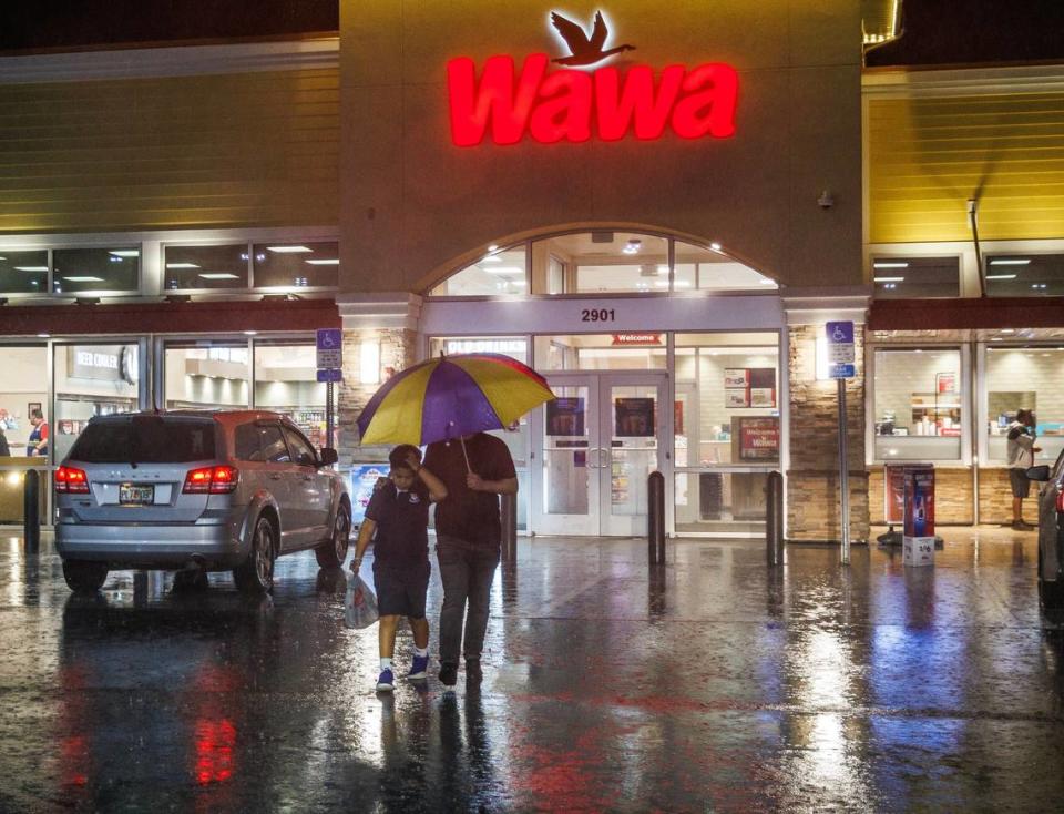 A man and a boy take cover under an umbrella as they walk out of a Wawa gas station located at West 29th Street and 16th Avenue in Hialeah as torrential downpours inundate South Florida due to a disturbance off Florida’s coast on Wednesday, November 15, 2023. Pedro Portal/pportal@miamiherald.com