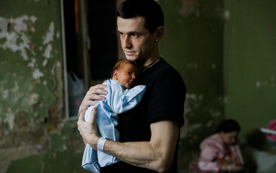 A man with his newborn child takes shelter in the basement of a perinatal centre as air raid siren sounds are heard in Kyiv.  - Reuters