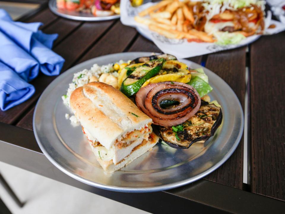 A sandwich, salad, and grilled vegetables on a plate.