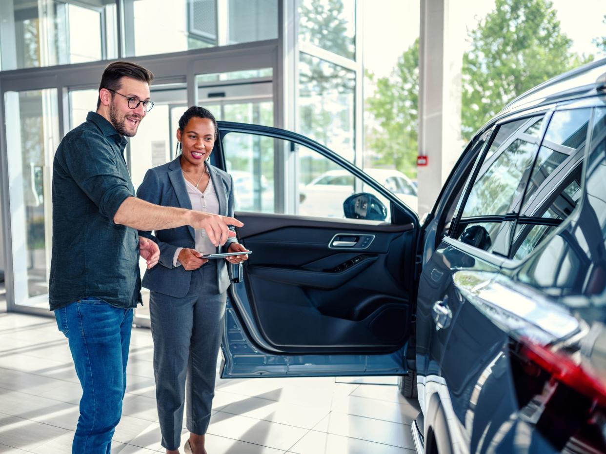 Saleswoman helping the male customer to choose a new car