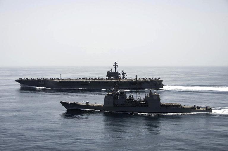 A US Navy handout photo released on April 21, 2015 shows the US aircraft carrier USS Theodore Roosevelt (back) and the guided-missile cruiser USS Normandy cooperating in the Arabian Sea as they conduct maritime security operations