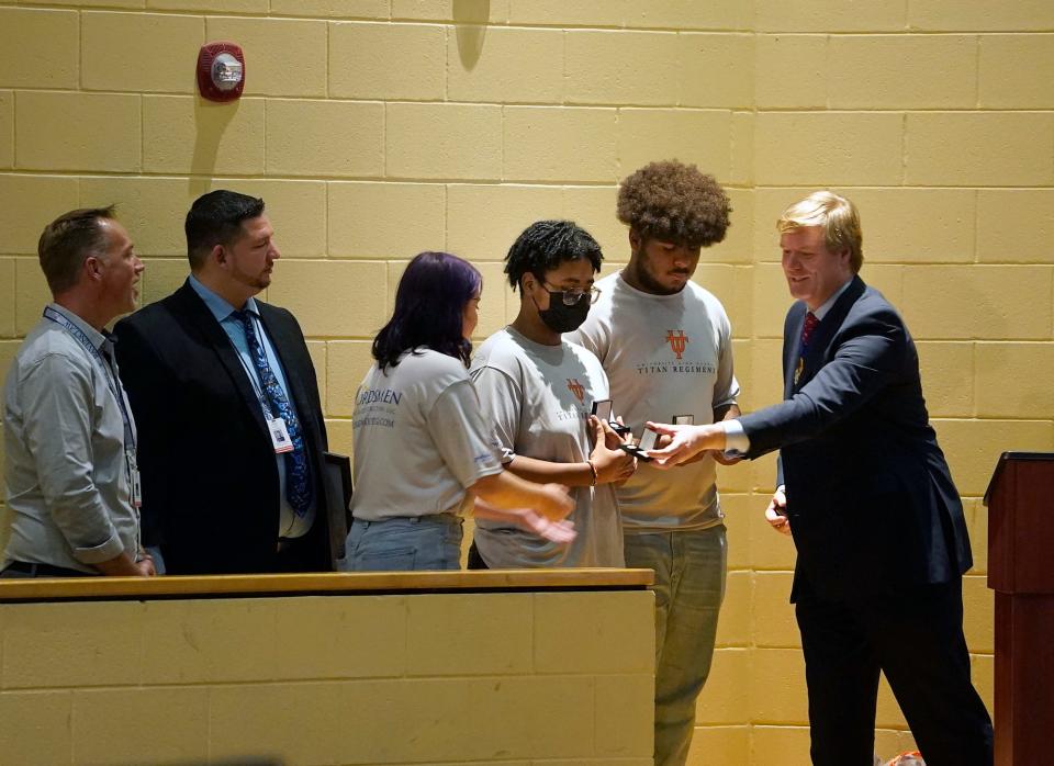 Former Lord Mayor of Westminster Duncan Sandys presents pins to University High School band drum majors Karissa Sibley, Jordan Mitchell and Ely's Guzman Rivera during a ceremony at the school to invite the band to perform in the 2024 London New Year's Day Parade, Wednesday, Nov. 16, 2022.