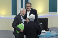 In this picture made available by Young Journalists Club, YJC, presidential candidates for June 18, elections Mohsen Mehralizadeh, left, Alireza Zakani, top, and Saeed Jalili, talk at the conclusion of a part of the final debate of the candidates at a state-run TV studio in Tehran, Iran, Saturday, June 12, 2021. Iran's seven presidential candidates offered starkly different views Saturday in the country's final debate, with hard-liners describing those seeking ties with the West as "infiltrators" and the race's sole moderate warning a hard-line government would only bring more sanctions for the Islamic Republic. (Morteza Fakhri Nezhad/ Young Journalists Club, YJC via AP)