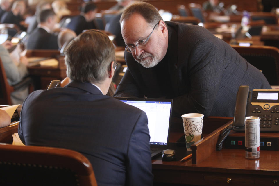 Kansas state Rep. Tobias Schlingensiepen, left, D-Topeka, confers with Rep. Bob Lewis, R-Garden City, during the House's session, Monday, March 25, 2024, at the Statehouse in Topeka, Kan. The House is now requiring its bills and resolutions to include the names of groups or lobbyists who sought the measures on them. (AP Photo/John Hanna)