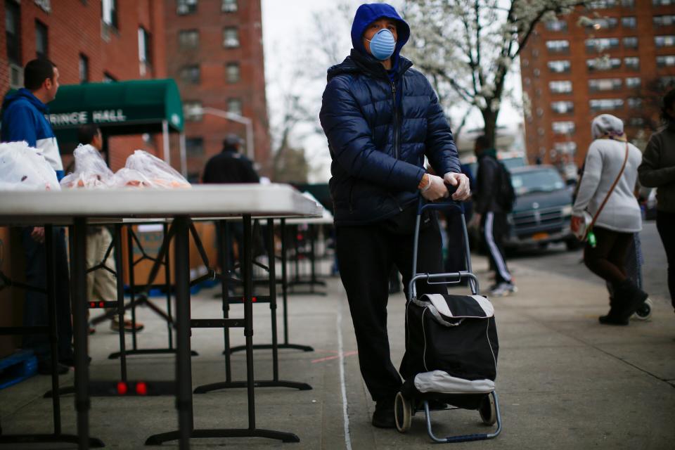 A man carries bags with food as volunteers from City Harvest distribute food in Harlem, New York City, on March 28. (Photo: KENA BETANCUR via Getty Images)