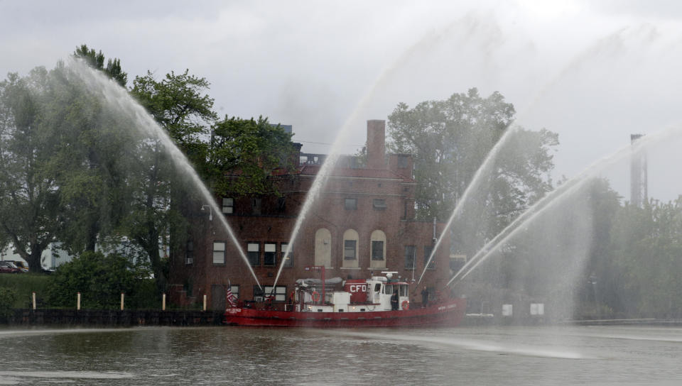 The Anthony J. Celebrezze turns on its hoses in front of Fire Station 21 on the Cuyahoga River, Thursday, June 13, 2019, in Cleveland. Fire Station 21 battles the fires on the Cuyahoga River. The Celebrezze extinguished hot spots on a railroad bridge torched by burning fluids and debris on the Cuyahoga in 1969. (AP Photo/Tony Dejak)