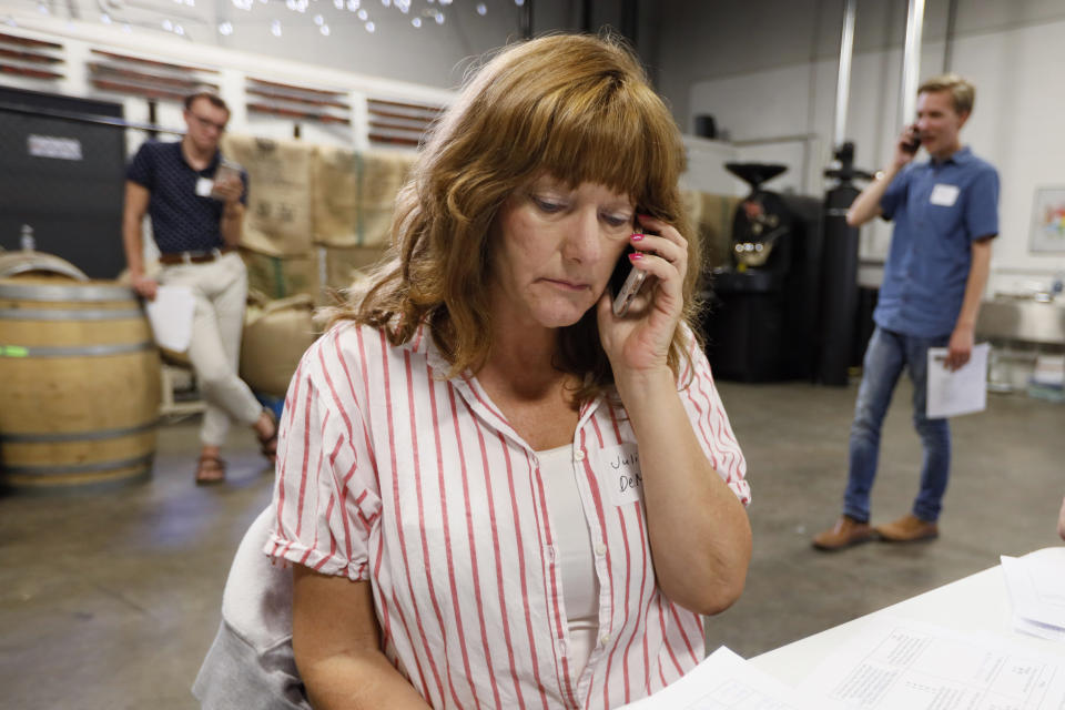 Democratic presidential candidate Pete Buttigieg supporter Julie DeMicco, center, talks on her cell phone during a "relational phone bank" at a local brewery, Thursday, Aug. 29, 2019, in West Des Moines, Iowa. The group worked their smartphones calling and texting friends to test their interest in the candidate. Buttigieg is well behind his better known rivals in Iowa who have spent months building a deep organizational structure in the state that marks the first test for the Democratic presidential nomination. But thanks to his campaign taking in nearly $25 million in contributions in the last quarter, money that he is using to help create an army of peer-to-peer foot soldiers, Buttigieg is rapidly trying to catch up. (AP Photo/Charlie Neibergall)