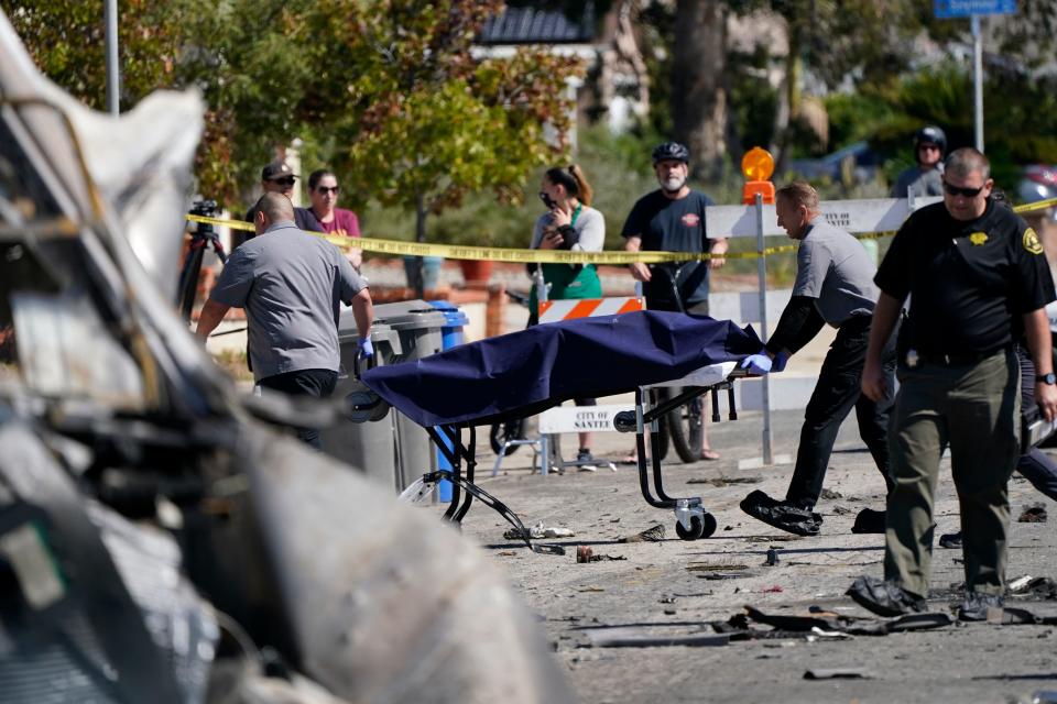 Officials from the San Diego County medical examiners office remove a gurney carrying remains from the site of a plane crash Tuesday, Oct. 12, 2021, in Santee, Calif.