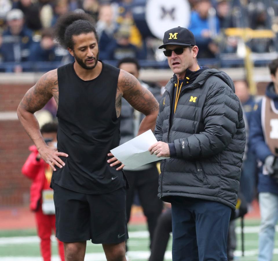 Jim Harbaugh goes over pass routes with former 49ers quarterback Colin Kaepernick at halftime of the Michigan spring game April 2, 2022 at Michigan Stadium in Ann Arbor.