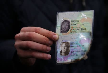 A local resident holds up identification cards of Laurens van der Graaff, which were found before being handed over to members of the recovery team, at the site of the MH17 crash near the village of Rozsypne (Rassypnoye), eastern Ukraine, November 11, 2014. REUTERS/Maxim Zmeyev