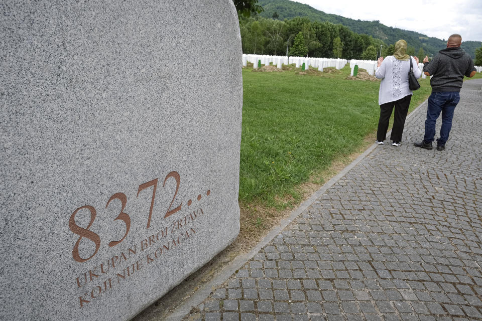 Visitors pray at the memorial cemetery in Potocari, near Srebrenica, Bosnia, Tuesday, July 7, 2020. Writing on stone translates "8372 victims, number is not final'. A quarter of a century after they were killed in Sreberenica, eight Bosnian men and boys will be laid to rest Saturday, July 11. Over 8,000 Bosnian Muslims perished in 10 days of slaughter after the town was overrun by Bosnian Serb forces in the closing months of the country’s 1992-95 fratricidal war. (AP Photo/Kemal Softic)