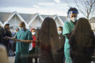 Maya Goode, a COVID-19 technician, performs a test as others wait their turn outside Asthenis Pharmacy in Providence, R.I., Tuesday, Dec. 7, 2021. Even as the U.S. reaches a COVID-19 milestone of roughly 200 million fully-vaccinated people, infections and hospitalizations are spiking, including in highly-vaccinated pockets of the country like New England. (AP Photo/David Goldman)