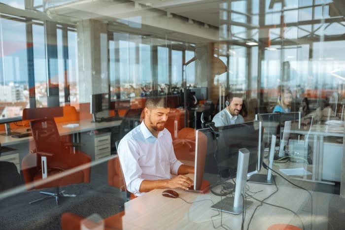 People at a row of desk's working in an office.