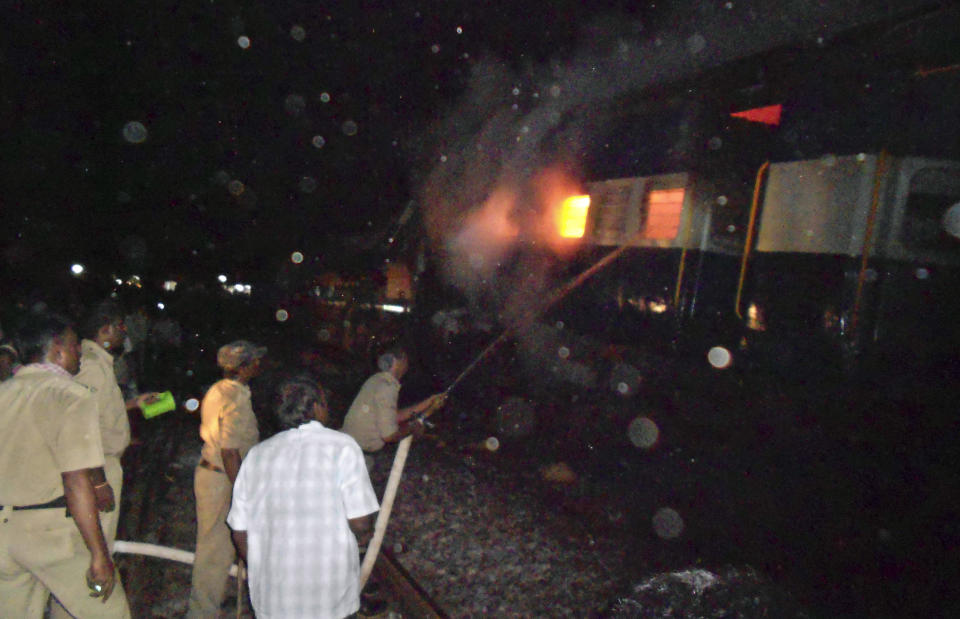 Firefighters and policemen try to douse flames on a train after an accident at a station near Penukonda, about 170 kilometers (105 miles) north of Bangalore, India, Tuesday, May 22, 2012. The passenger train rammed into a parked freight train and burst into flames before dawn Tuesday, killing more than a dozen people in southern India, officials said. (AP Photo)