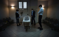 Sabatino Di Girolamo, center, mayor of Roseto degli Abruzzi, with his son Francesco, right, and his sister Marisa Di Felice, mourns his mother Annunziata, laid in state in the morgue of the Giuseppe Mazzini Hospital in Teramo, central Italy, Tuesday, May 12, 2020. (AP Photo/Domenico Stinellis)