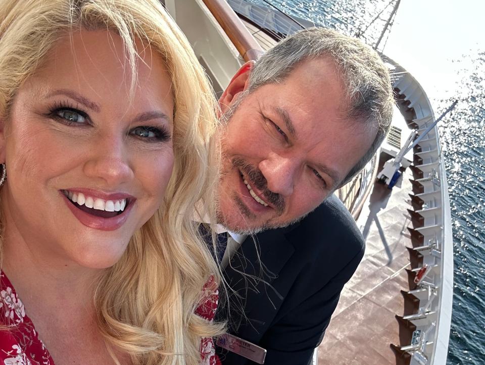 Christine Kesteloo and her husband in a uniform smiling on top of a cruise ship