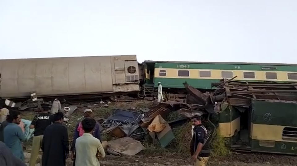 People gather around the scene of a collision between two trains in Ghotki.