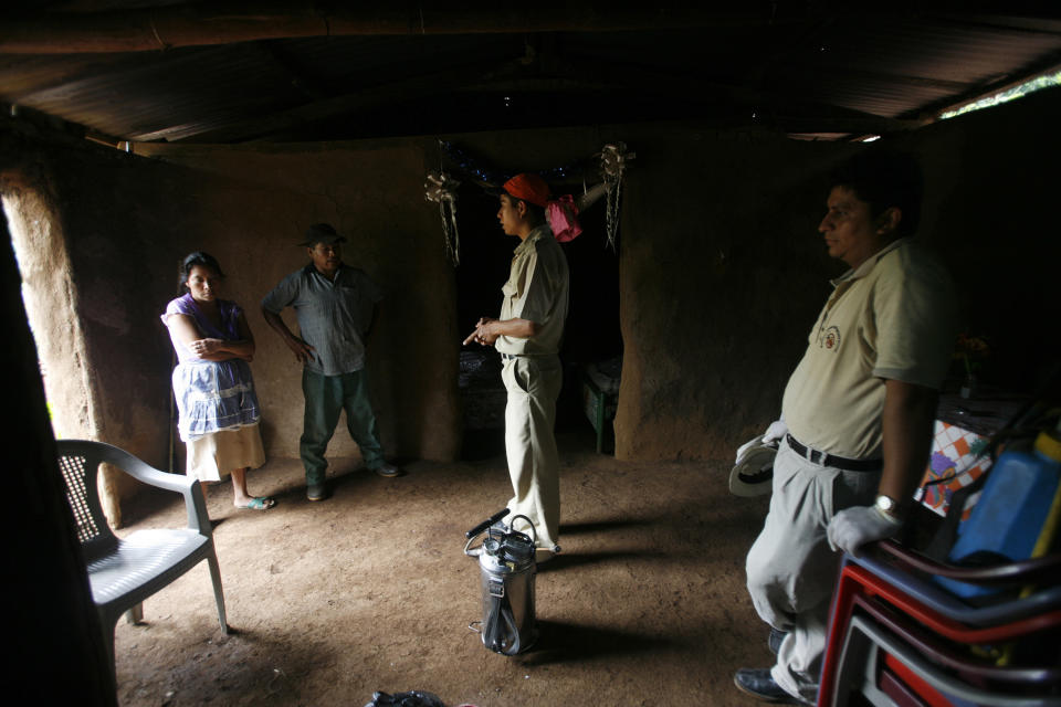 Guatemalan health inspectors speak to a family before fumigating their adobe hut, which is infested with kissing bugs.&nbsp; (Photo: Daniel Leclair / Reuters)