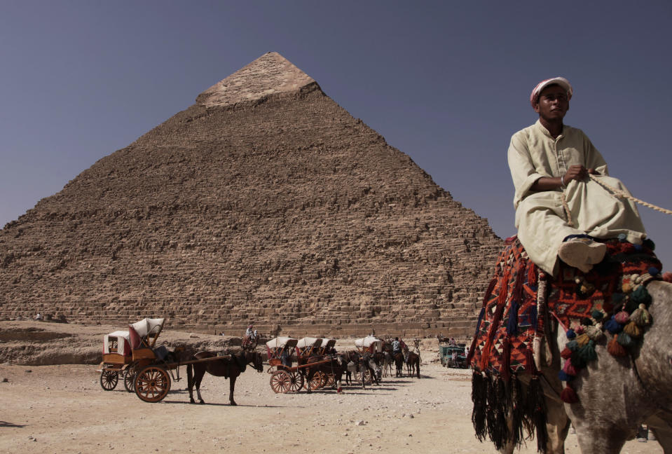 An Egyptian camel owner waits for customers to take a ride, in front of the Khafre pyramid, near Cairo, Egypt (AP Photo/Nariman El-Mofty, File)