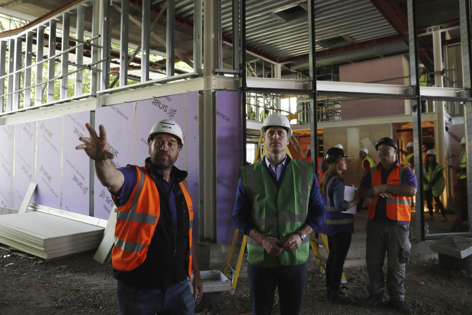 Britain's Prince William, center, with television presenter Nick Knowles, left, joins the crew of television programme DIY SOS in west London, Tuesday May 15, 2018, on a major project to support people affected by the fire at Grenfell Tower. (Adrian Dennis/Pool via AP)