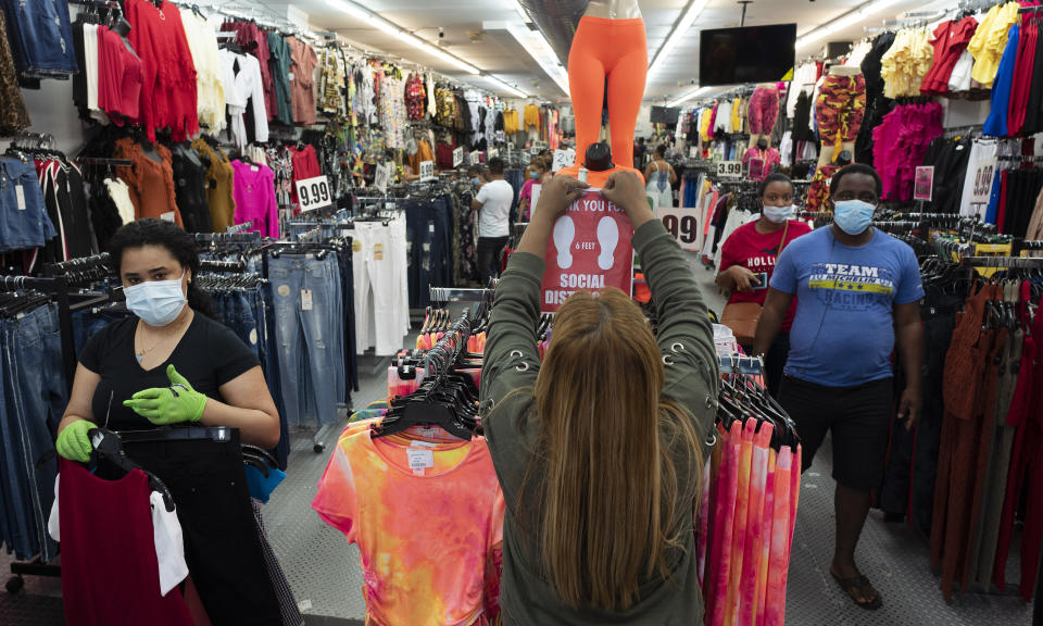 Sonia Singh, the manager of Ashley 21 clothing store, tapes up a social distancing sign, Tuesday, June 9, 2020, in Mount Vernon, N.Y. Counties north of New York City are reopening clothing stores as part of Phase 2 during the coronavirus pandemic. (AP Photo/Mark Lennihan)