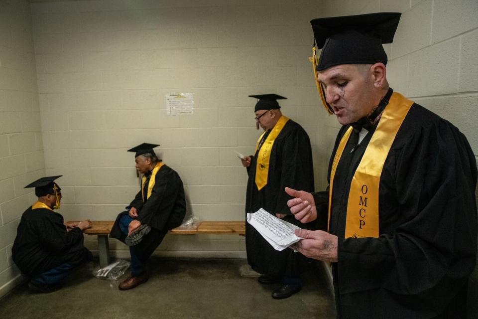 Four men in cap, gown and yellow sashes practice speeches