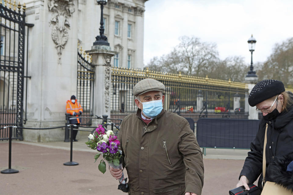 A man carries flowers outside Buckingham Palace, London, Monday, April 12, 2021. Britain's Prince Philip, the irascible and tough-minded husband of Queen Elizabeth II who spent more than seven decades supporting his wife in a role that mostly defined his life, died on Friday. (Luciana Guerra/PA via AP)