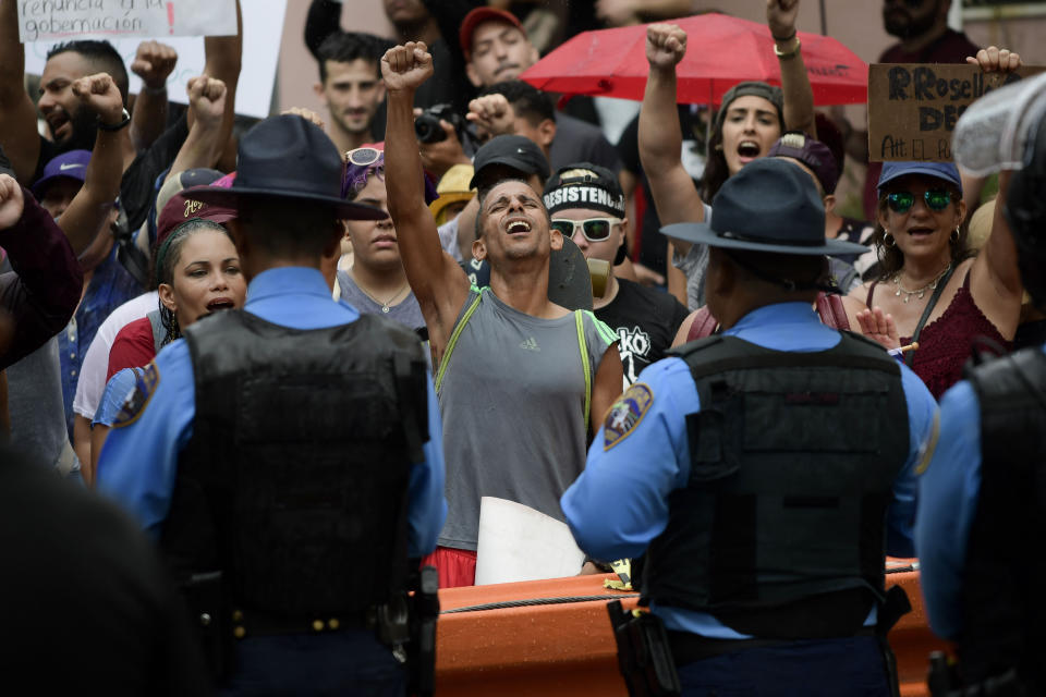 People raise their fists and sing the Puerto Rican Revolutionary Hymn during a protest near La Fortaleza governor's residence in San Juan, Puerto Rico, Sunday, July 14, 2019. Protesters are demanding Gov. Ricardo Rosselló step down for his involvement in a private chat in which he used profanities to describe an ex-New York City councilwoman and a federal control board overseeing the island's finance. (AP Photo/Carlos Giusti)