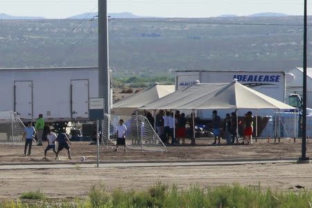 Hijos de inmigrantes detenidos juegan fútbol en un campamento recién construido, visto a través de una valla fronteriza cerca de un puerto de entrada de la oficina de Aduanas y Protección Fronteriza de EEUU en Tornillo, Texas, EEUU, el 18 de junio de 2018. REUTERS/Jose Luis Gonzalez