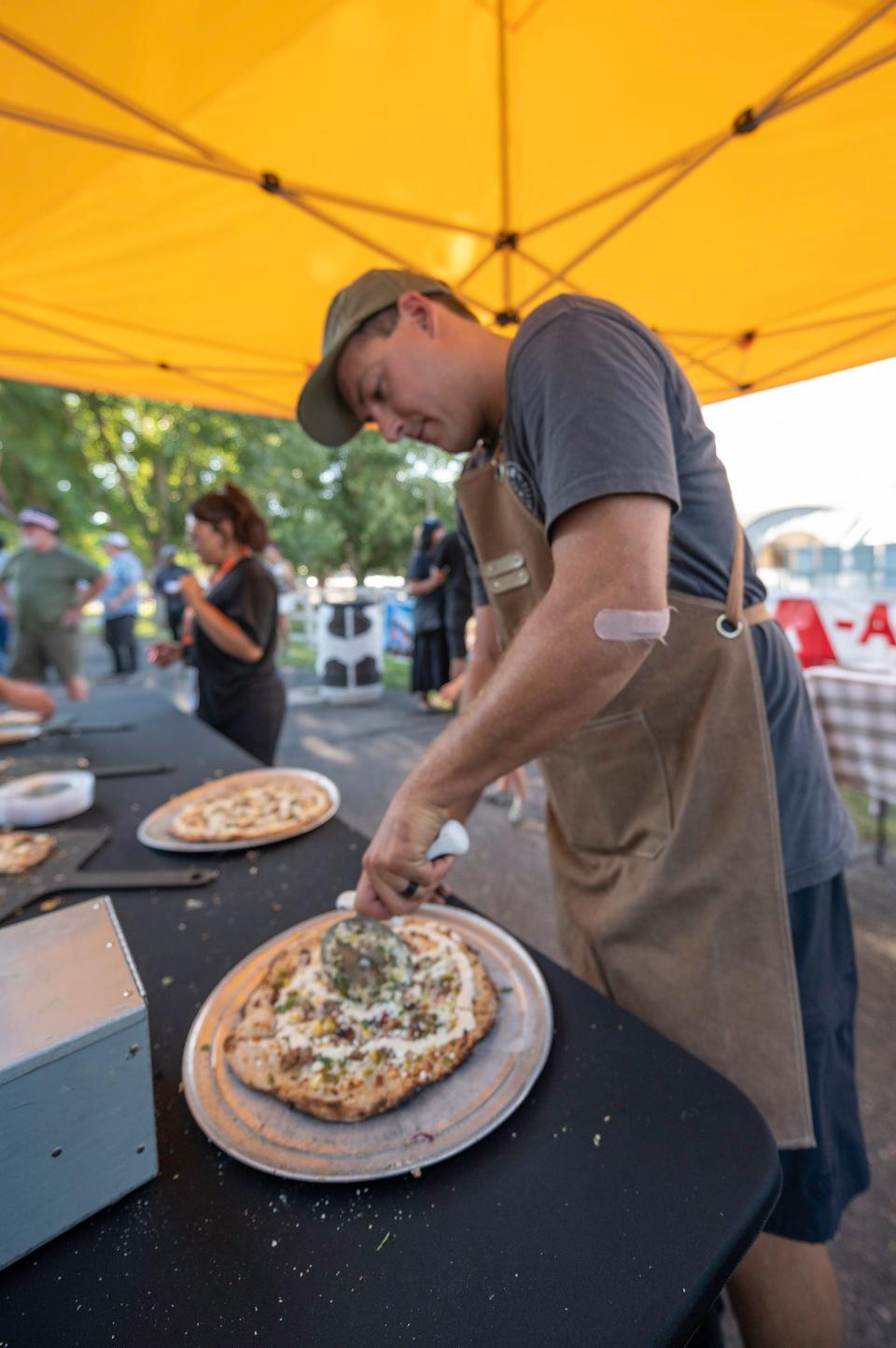 Wes Latka slices pizza at the Stoke Pizza setup during the Governor's Plate competition at the Colorado State Fair on Tuesday, August 29, 2023.