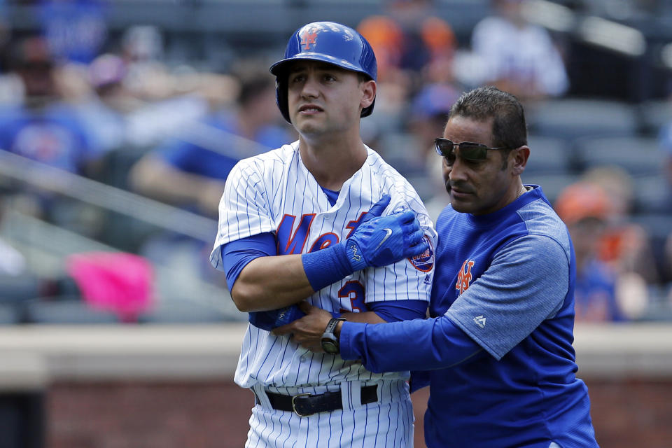 Ray Ramirez helps Michael Conforto off the field after an injury. (AP)