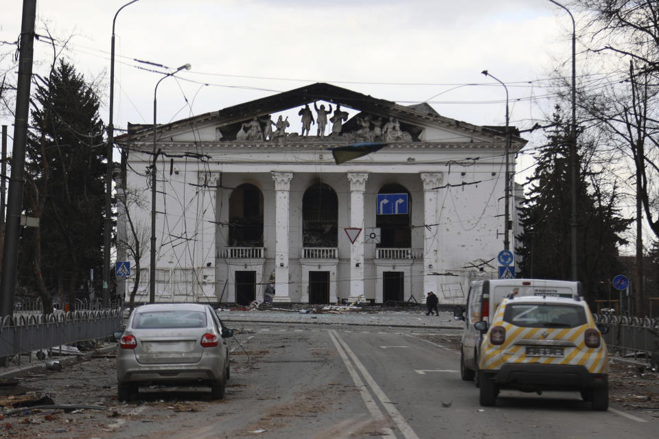 FILE - People walk past the Donetsk Academic Regional Drama Theatre in Mariupol, Ukraine, following a March 16, 2022, bombing of the theater, which was used as a shelter, in an area now controlled by Russian forces on Monday, April 4. On the battlefields of Ukraine, the fog of war plagues soldiers. A related issue afflicts those who are far from the fighting but avid to learn developments in the vast war. Disinformation, misinformation and absent information all cloud civilians’ understanding. Officials from each side denounce devious plots being prepared by the enemy, which never materialize. (AP Photo/Alexei Alexandrov, File)