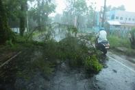 A man rides his bike past fallen tree branches along a road ahead of the expected landfall of cyclone Amphan in Digha, West Bengal, on May 20, 2020. - India and Bangladesh began evacuating more than two million people on May 18 as a cyclone barrelled towards their coasts, with officials racing to ready extra shelters amid fears of coronavirus contagion in cramped refuges. (Photo by Dibyangshu SARKAR / AFP) (Photo by DIBYANGSHU SARKAR/AFP via Getty Images)