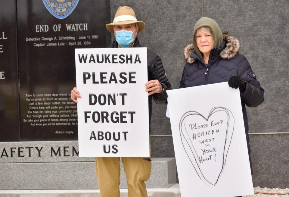 RJ and Patricia Esposito held signs outside of Waukesha City Hall urging the city to not forget those who lost their homes one year ago.