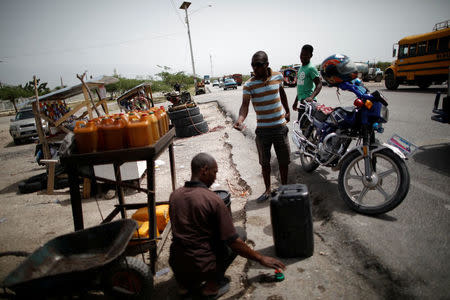 A man buys gasoline at a stand displaying fuel for sale on the outskirts of Port-au-Prince, Haiti, July 12, 2018. REUTERS/Andres Martinez Casares