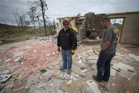 Seth Parker (L) and a friend look down at what is left of Parker's house in Vilonia, Arkansas April 30, 2014. REUTERS/Carlo Allegri