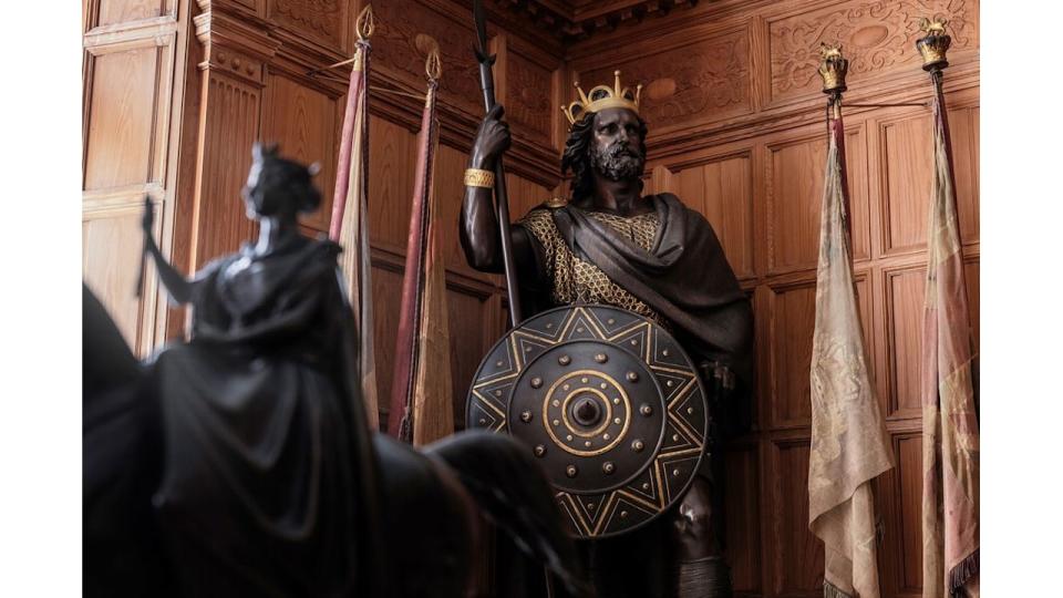 A large black statue in the corner of a wooden-panelled room