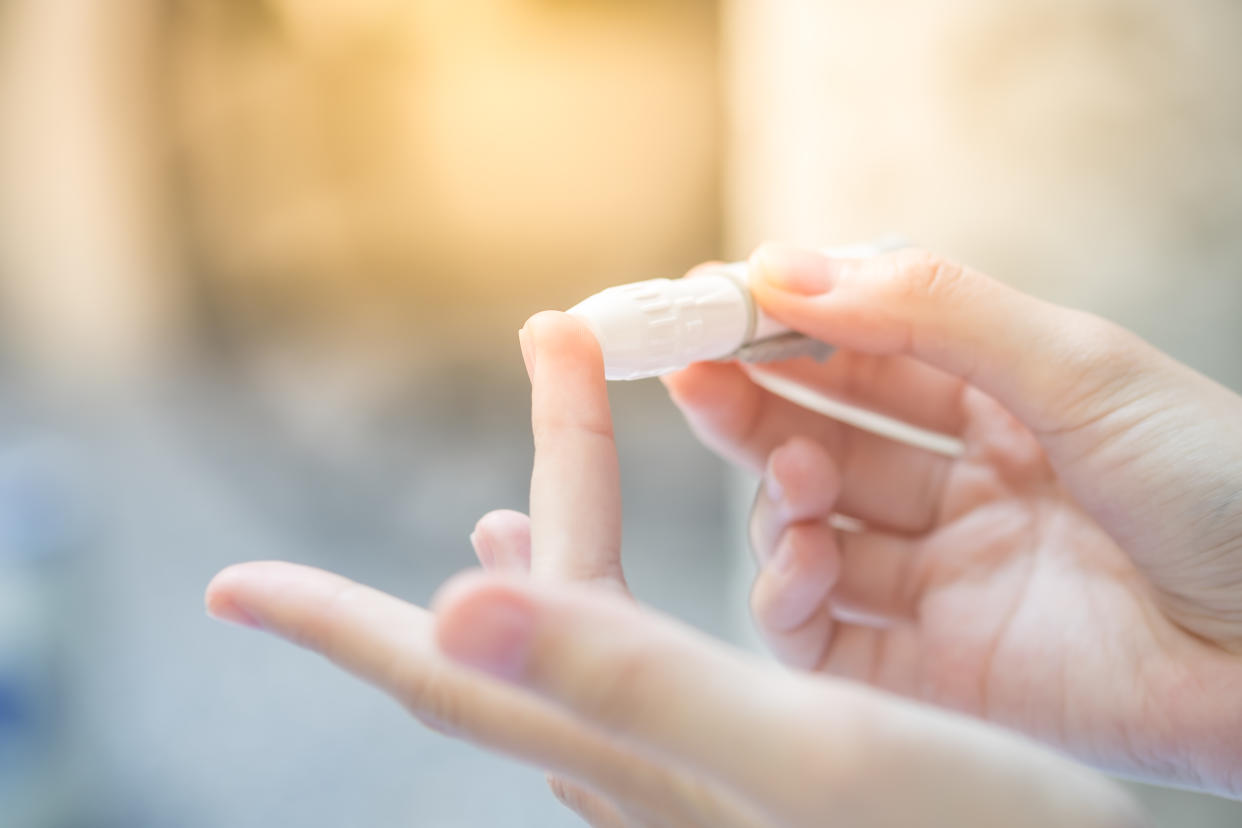 Close up of asian woman hands using lancet on finger to check blood sugar level by glucose meter, Healthcare medical and check up, diabetes, glycemia, and people concept